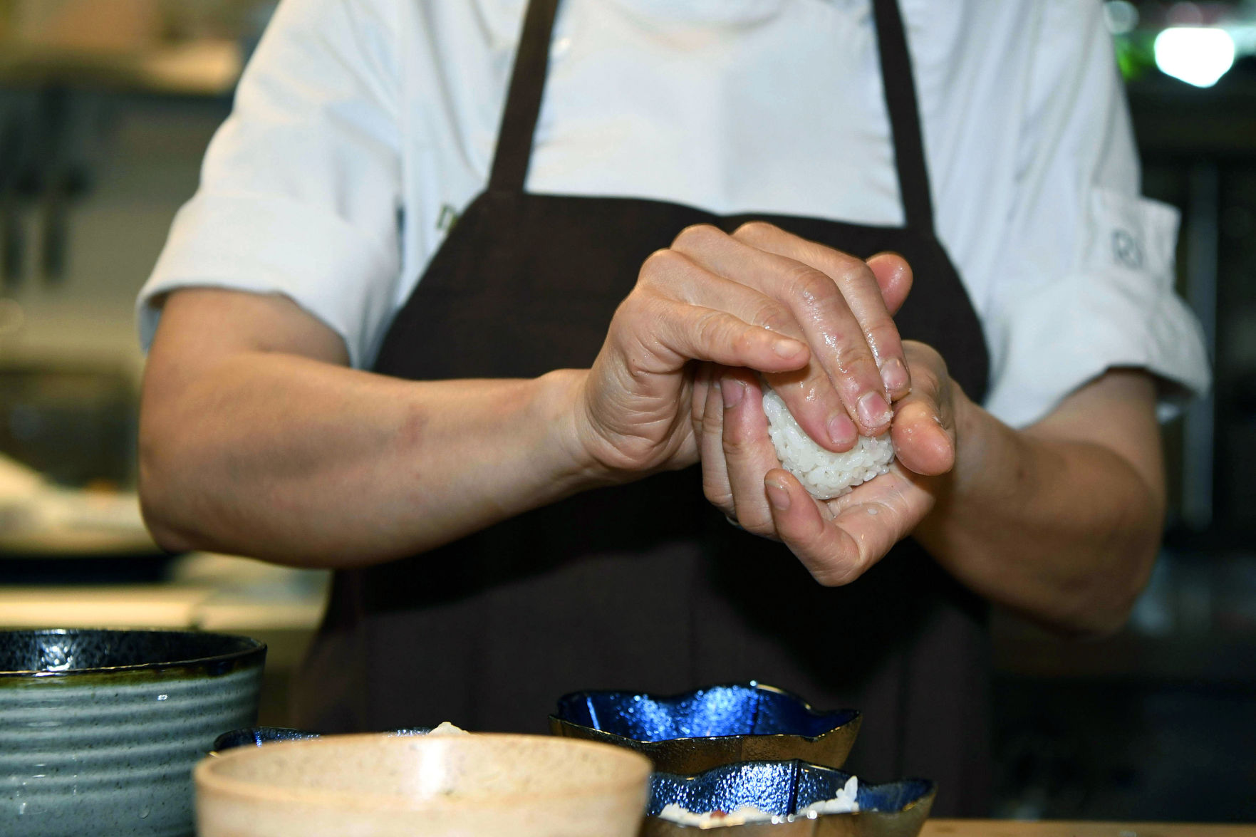 To shape onigiri, gently squeeze into a triangle shape with damp hands that have been sprinkled with salt to season the rice.